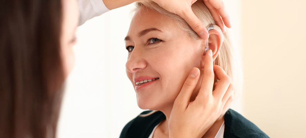 Mujer mayor con problemas de oído yendo al centro auditivo
